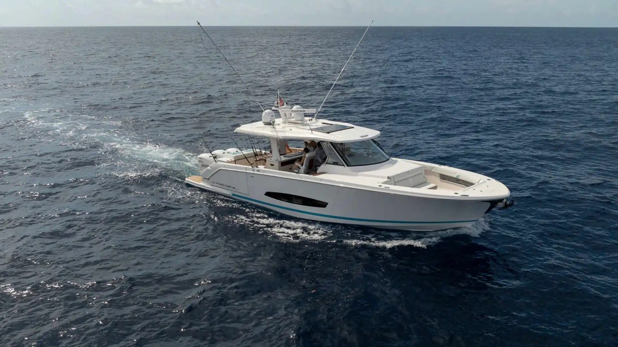 White motorboat cruising on open sea under a partly cloudy sky.