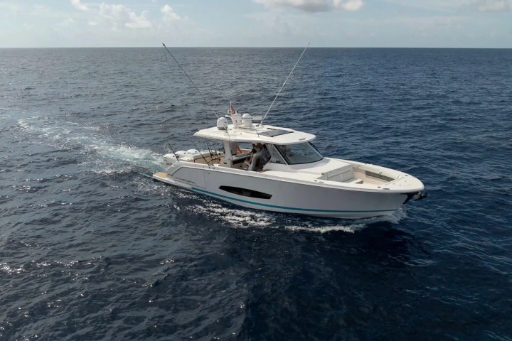 White motorboat cruising on open sea under a partly cloudy sky.