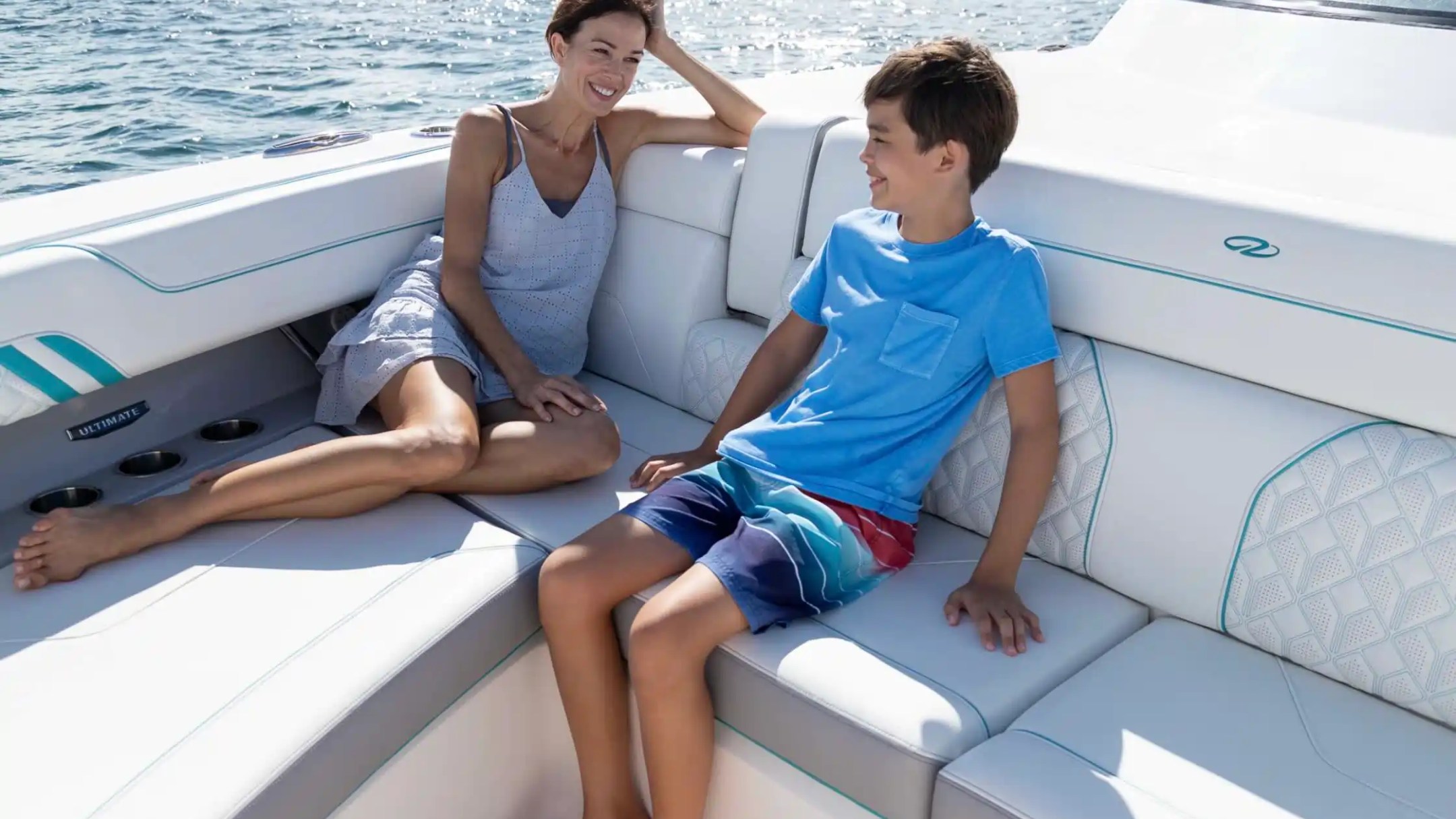 Woman and boy smiling on a boat with water in the background.