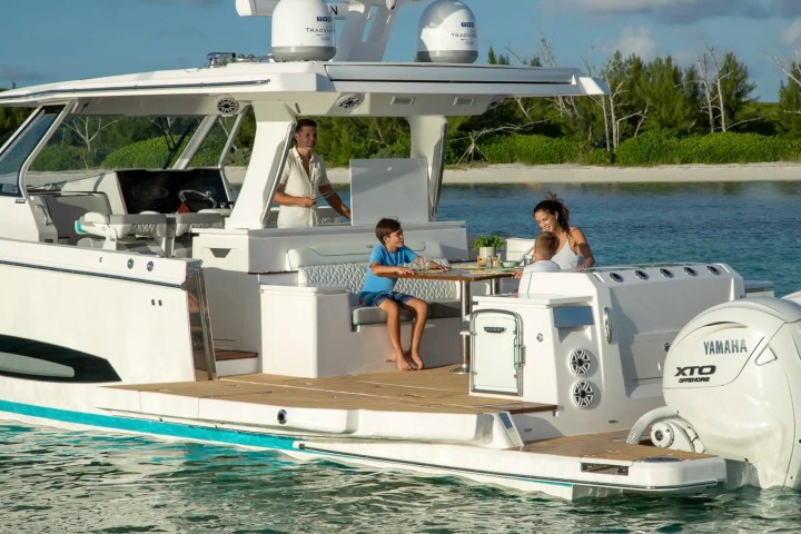 Family enjoying a meal on a boat docked near a green shoreline.