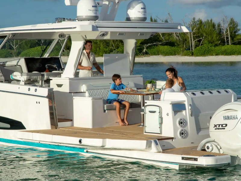 Family enjoying a meal on a boat docked near a green shoreline.