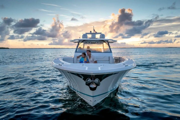 People sitting on a boat in the ocean at sunset with cloudy sky.