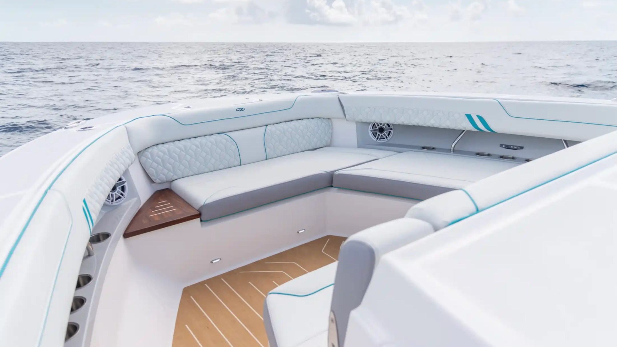 Luxury boat seating with quilted cushions overlooking the ocean under a partly cloudy sky.