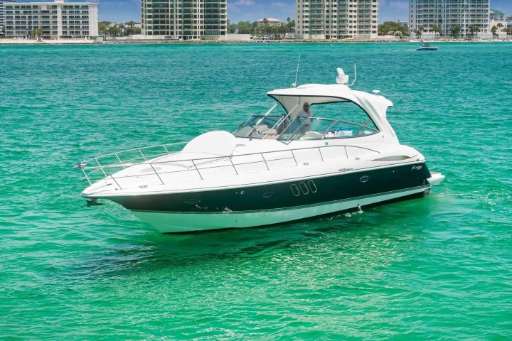 White yacht on turquoise water with city skyline in the background.