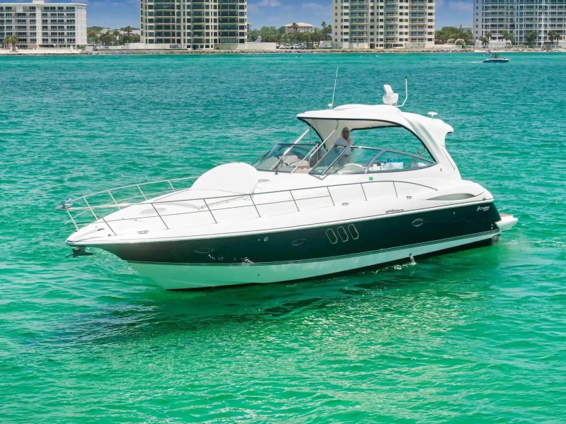 White yacht on turquoise water with city skyline in the background.