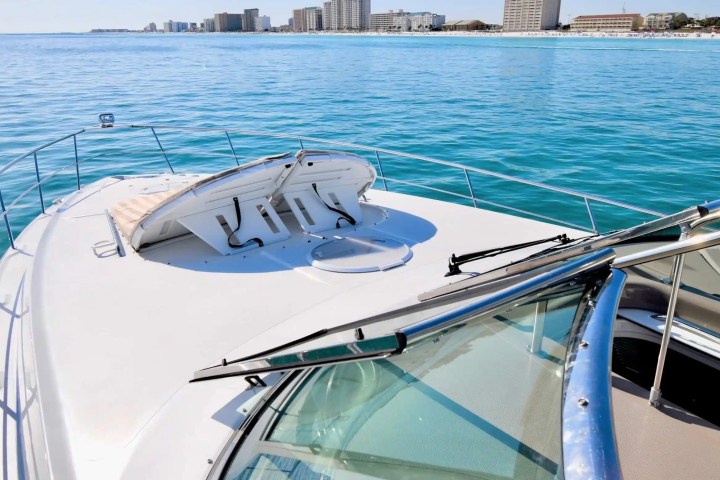 View from yacht deck over clear ocean towards distant city skyline.
