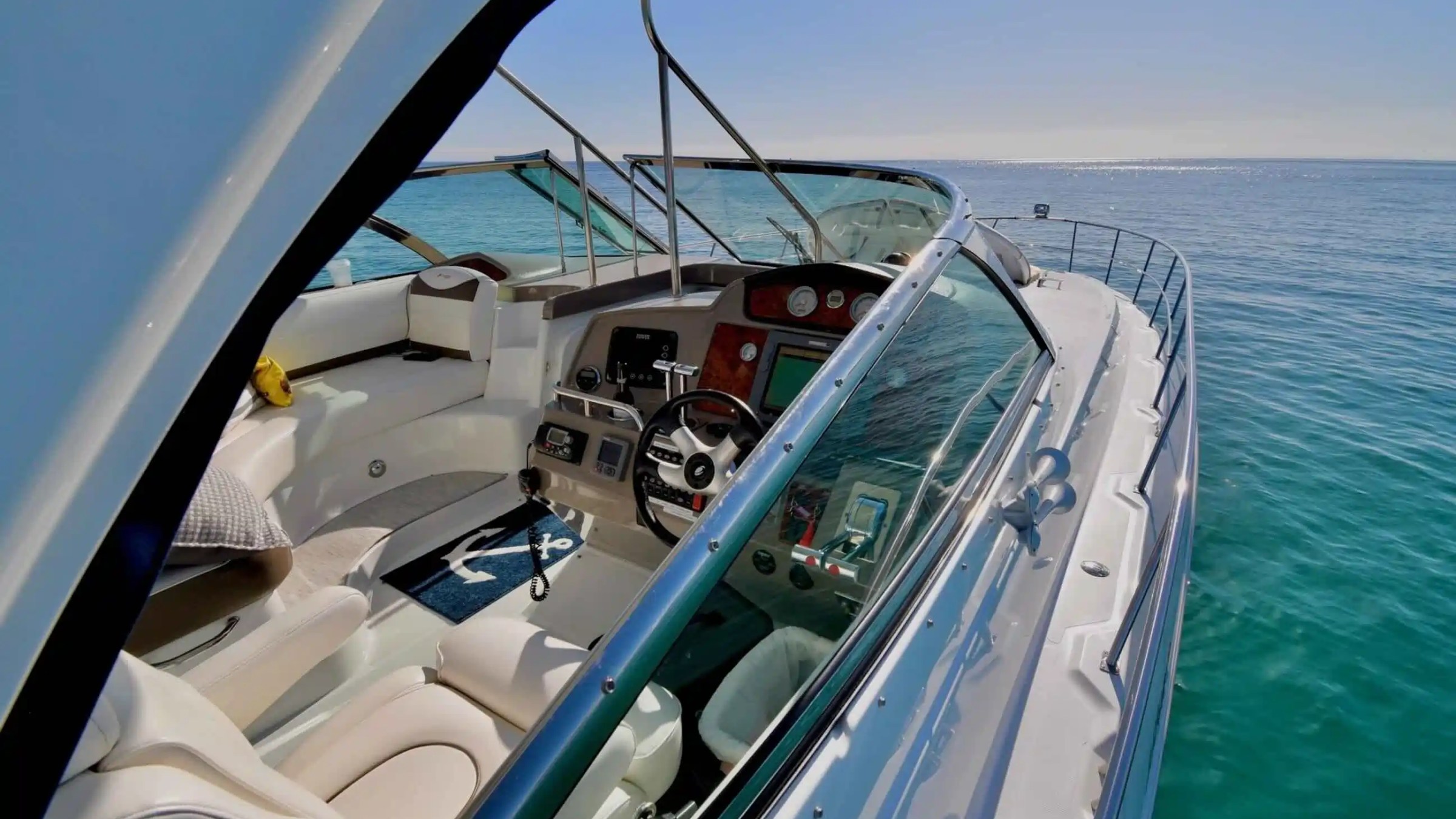 View of a yacht's cockpit and steering wheel overlooking a calm sea.