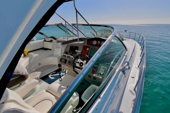 View of a yacht's cockpit and steering wheel overlooking a calm sea.