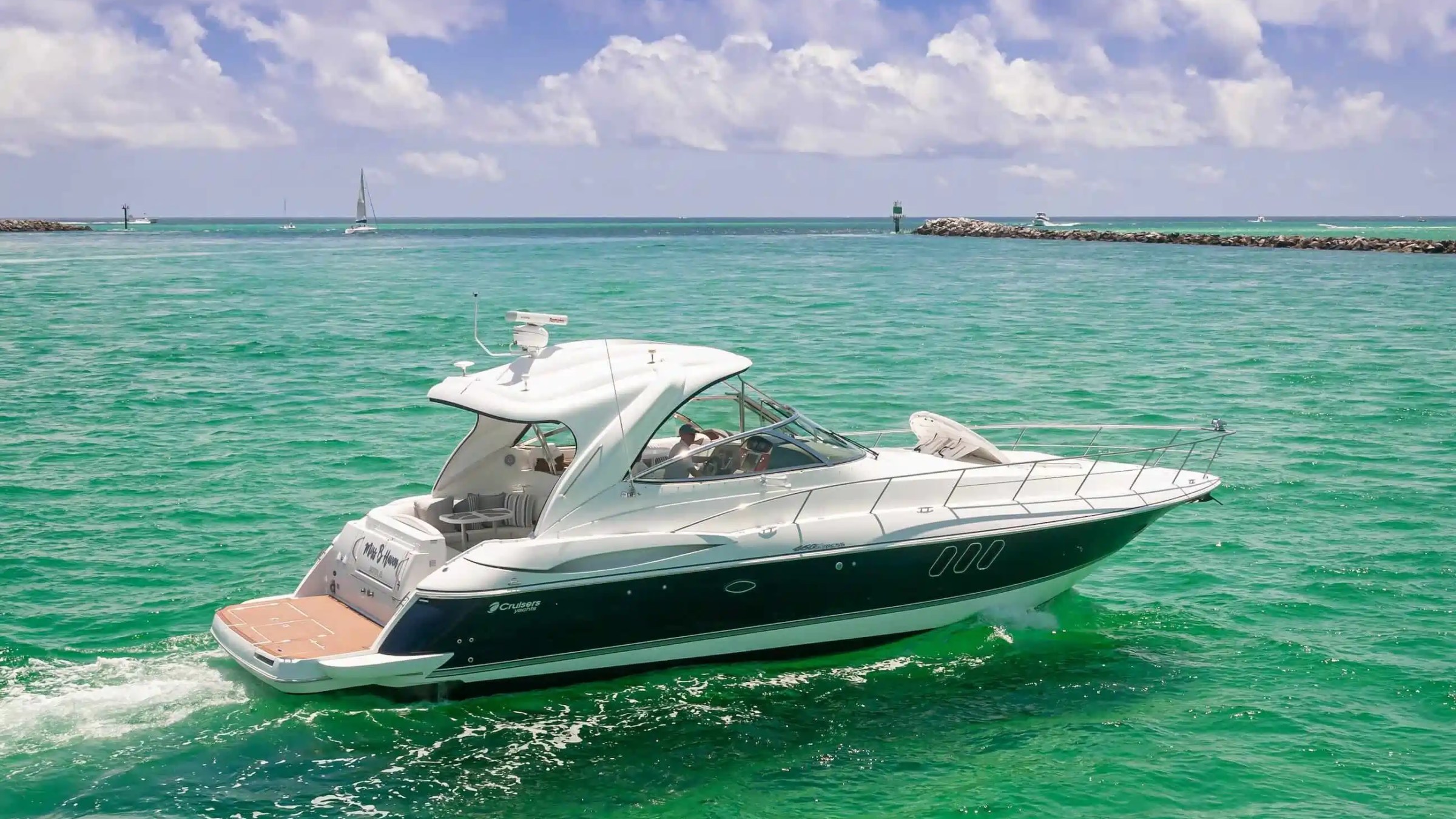Motor yacht cruising in turquoise water under a partly cloudy sky.
