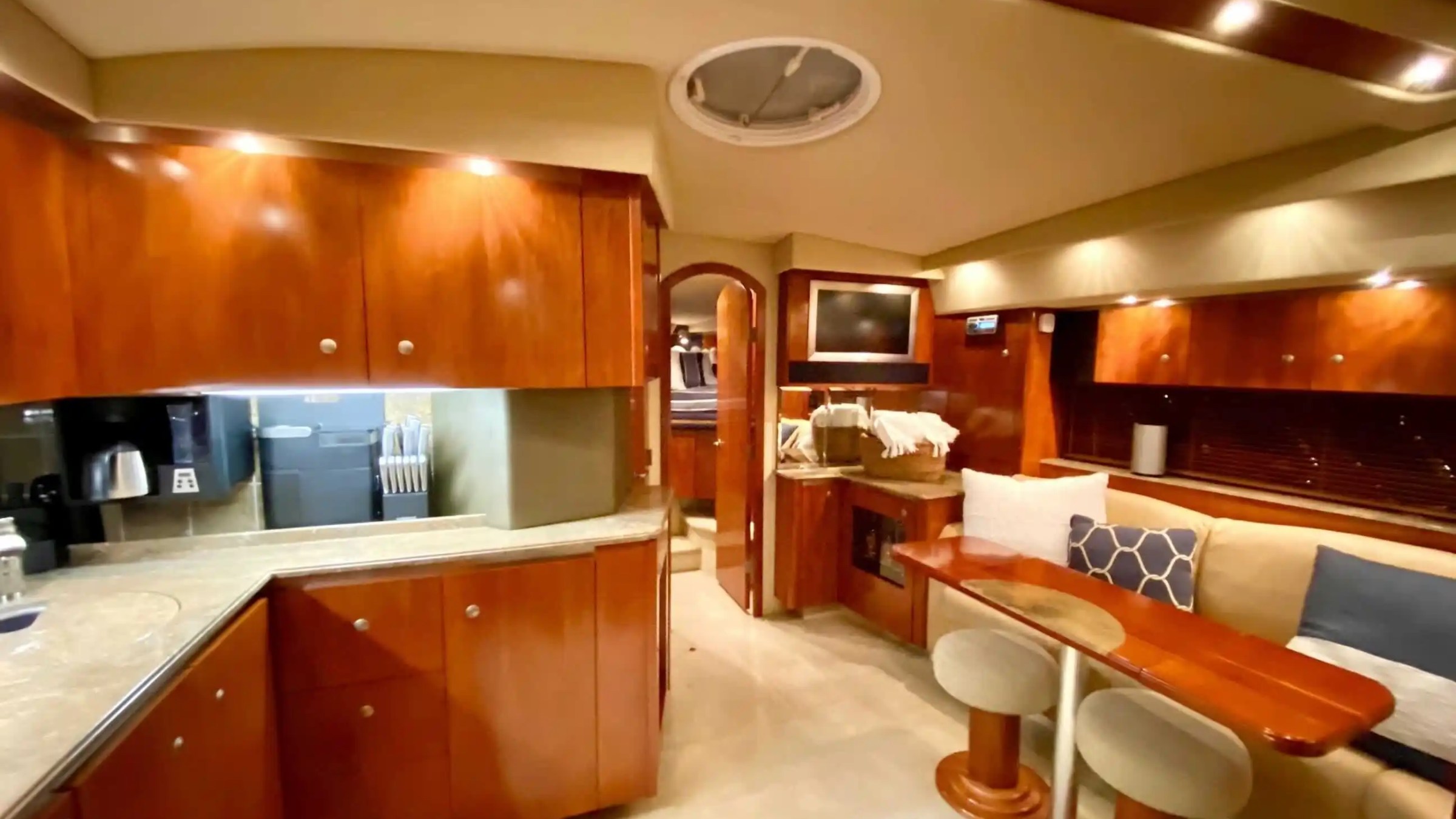 Luxurious yacht interior with wooden cabinets, dining area, and a small kitchen.