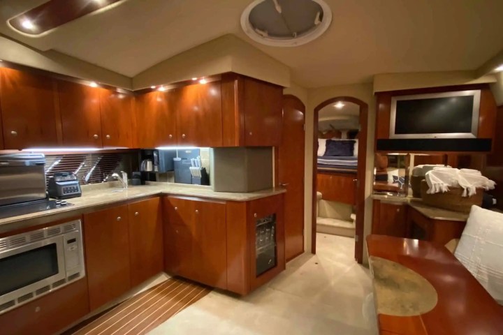 Luxurious yacht interior with kitchen, dining area, and bedroom.