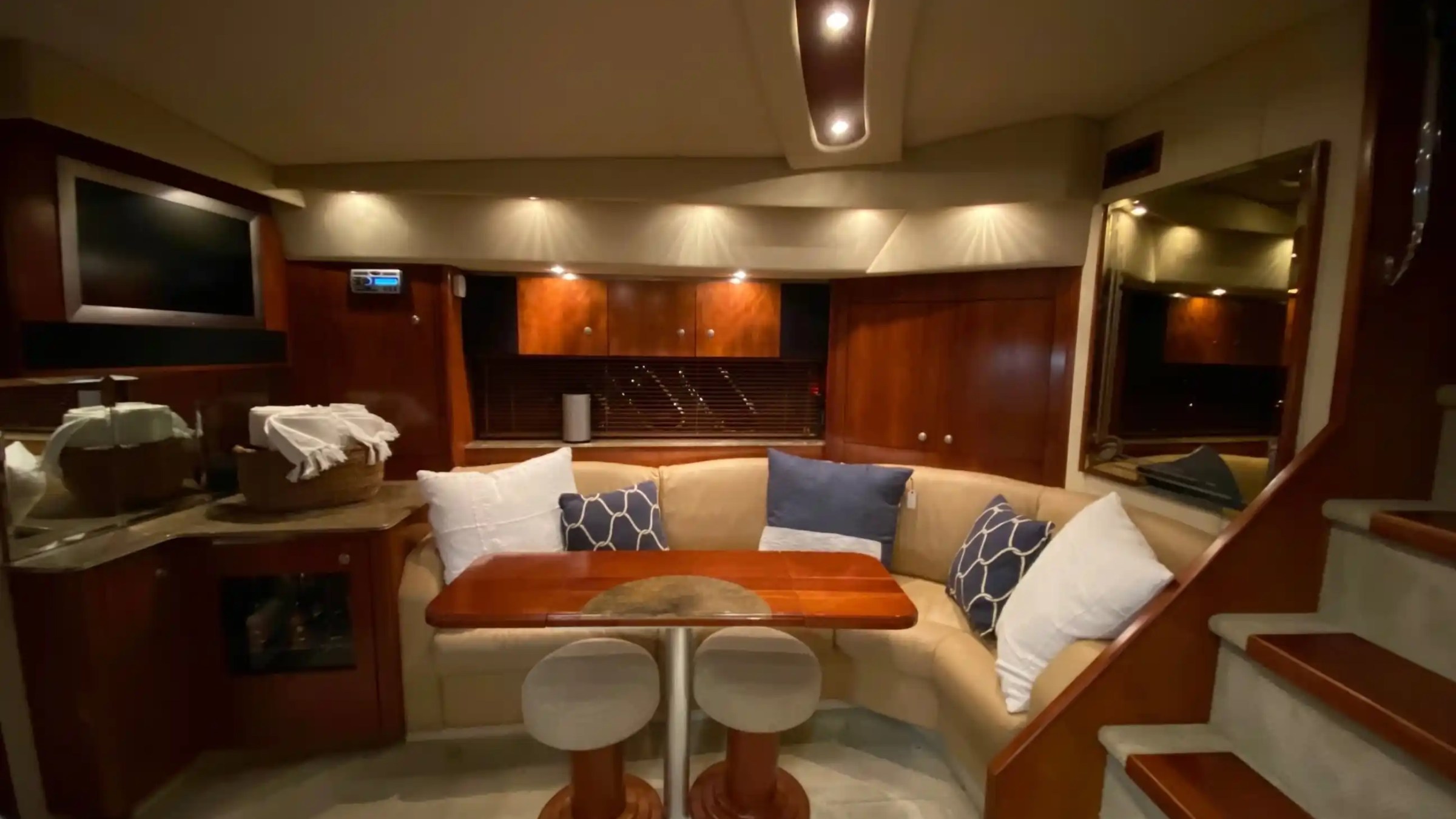 Cozy yacht interior with curved sofa, cushions, small table, and built-in TV.