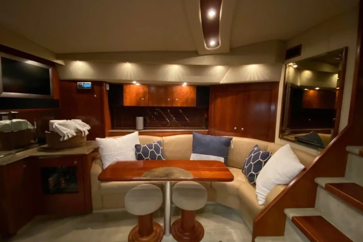 Cozy yacht interior with curved sofa, cushions, small table, and built-in TV.