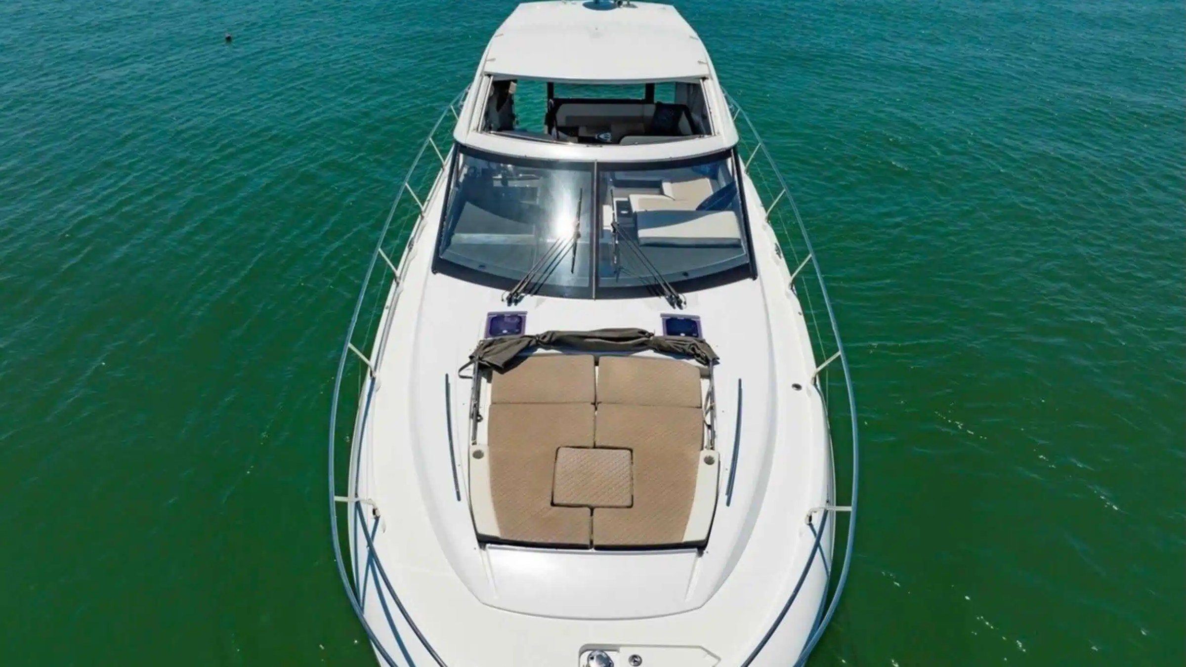A yacht with a sunbed on its deck, floating on blue-green water.