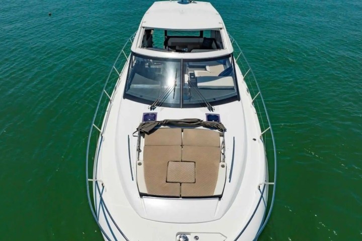 A yacht with a sunbed on its deck, floating on blue-green water.