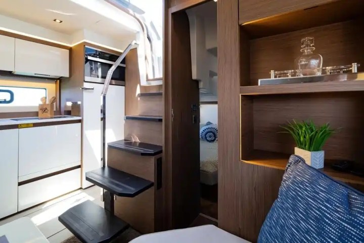 Stylish yacht interior with kitchen, wooden stairs, and a cozy seating area.