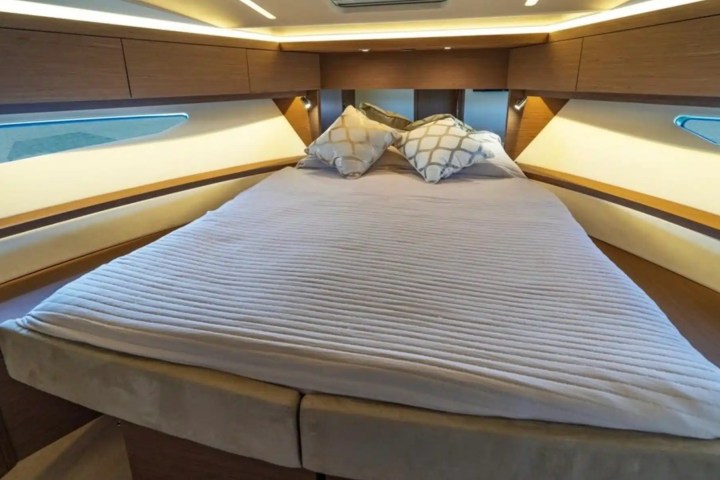 Cozy boat cabin with a double bed, striped bedding, and decorative pillows.