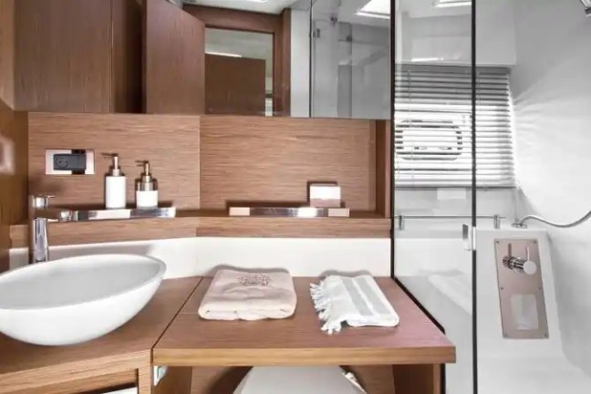 Modern bathroom with wooden cabinetry, round sink, and glass shower enclosure.