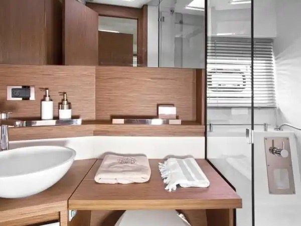 Modern bathroom with wooden cabinetry, round sink, and glass shower enclosure.