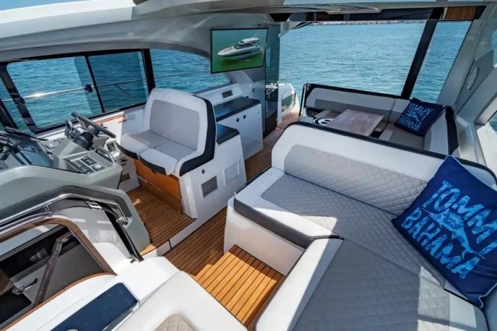 Interior of a yacht with plush seating, nautical decor, and ocean view through windows.