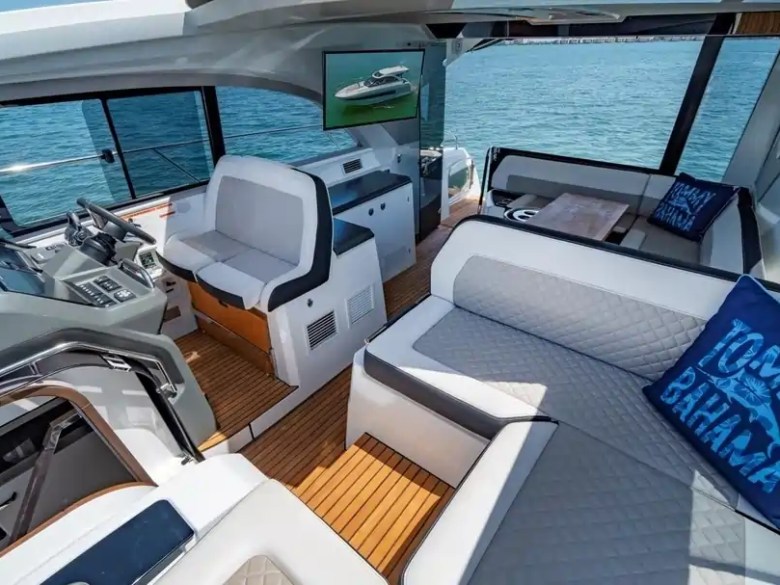 Interior of a yacht with plush seating, nautical decor, and ocean view through windows.