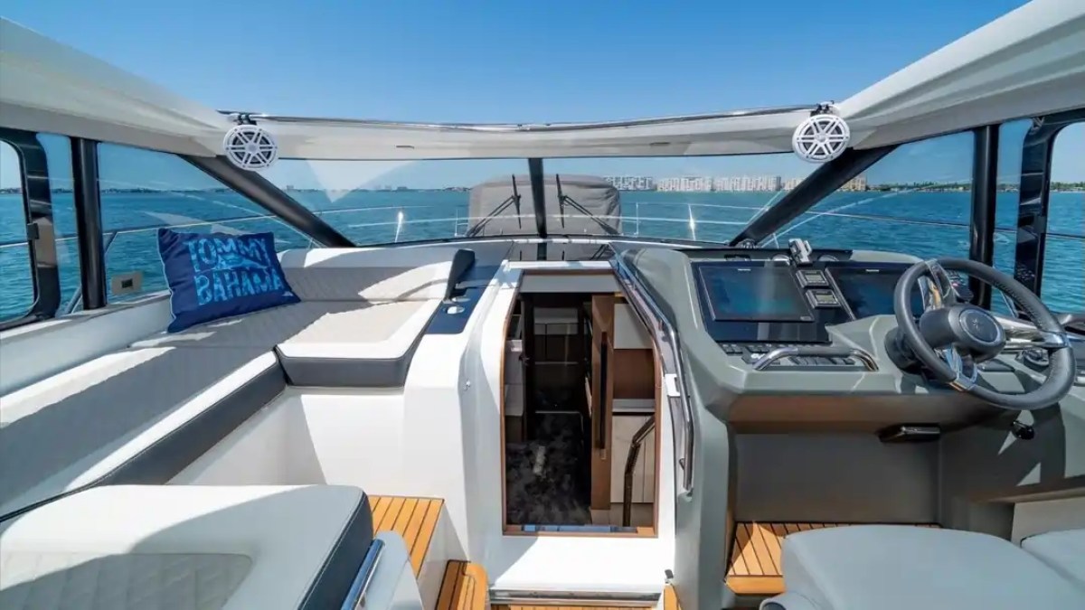 Inside a boat cockpit with seating, controls, and a sea view.