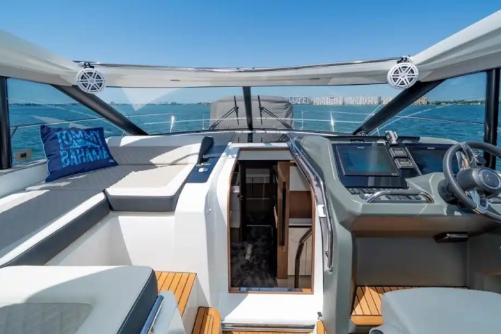 Inside a boat cockpit with seating, controls, and a sea view.