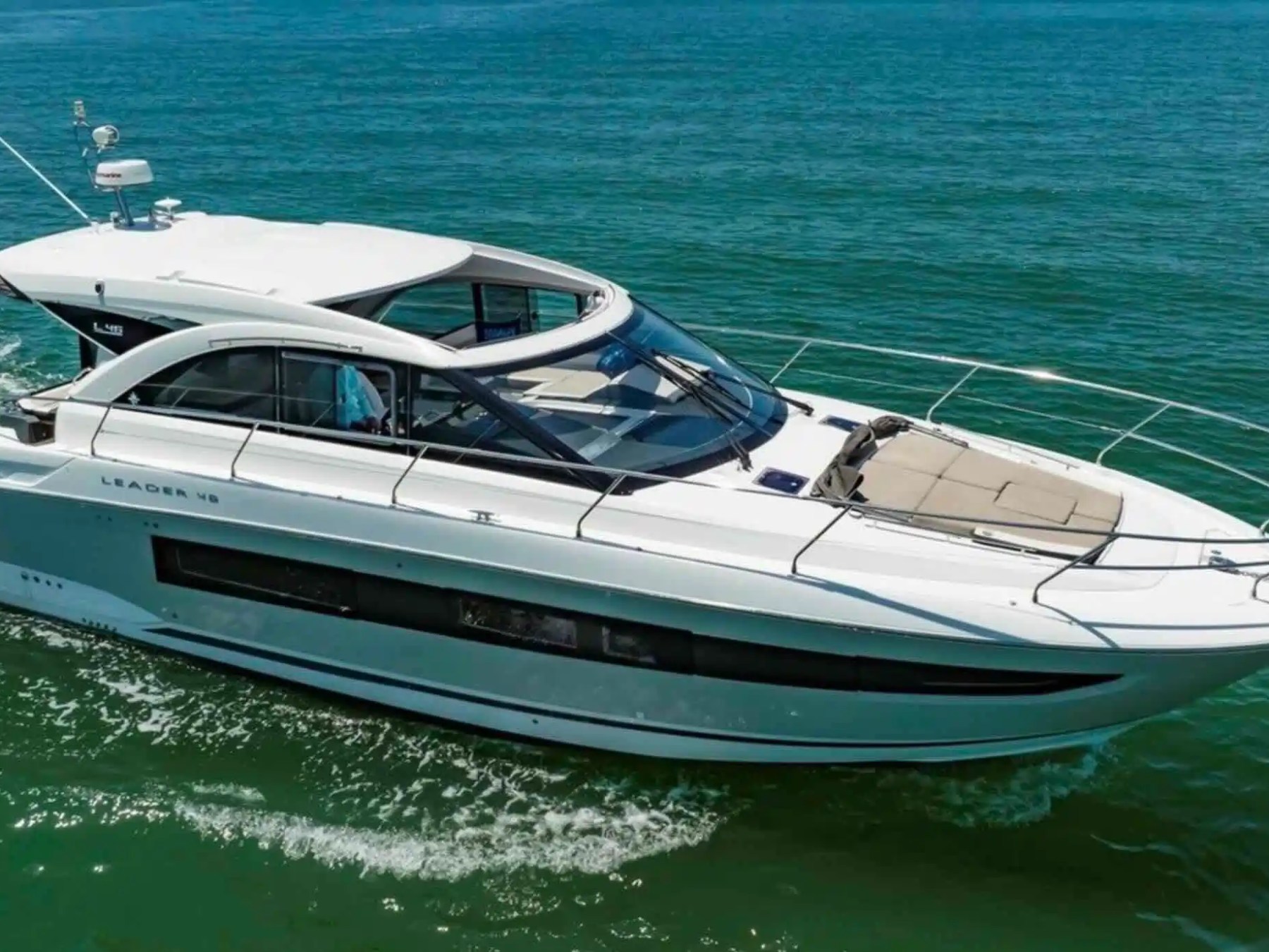 White motor yacht cruising on calm blue water.