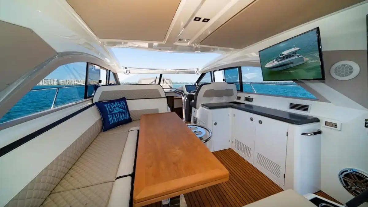 Interior of a luxury yacht with seating, table, TV, and ocean view.