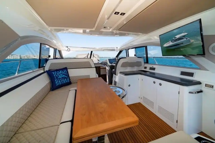 Interior of a luxury yacht with seating, table, TV, and ocean view.