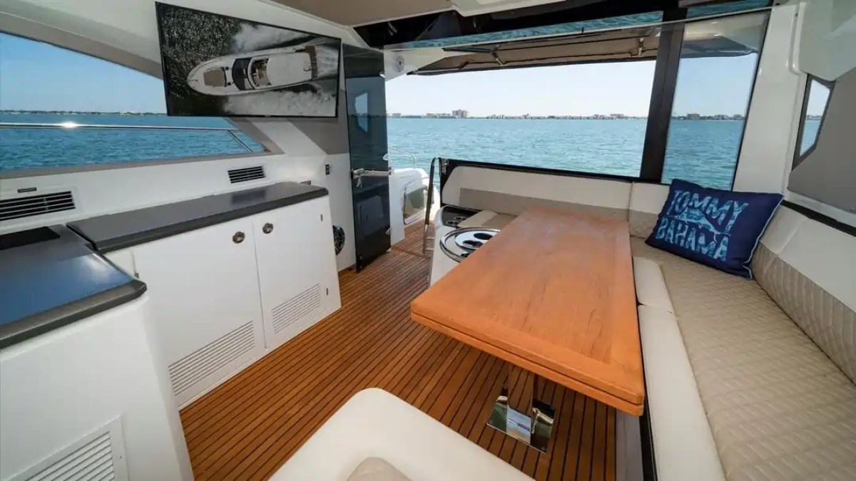 Luxurious yacht interior with wooden floors, seating, table, and sea view.