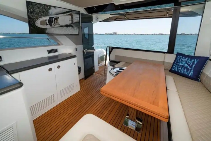 Luxurious yacht interior with wooden floors, seating, table, and sea view.