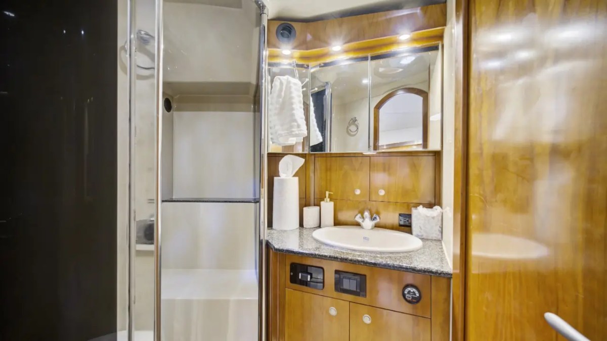 Modern bathroom with wood cabinets, shower, and sink with toiletries.