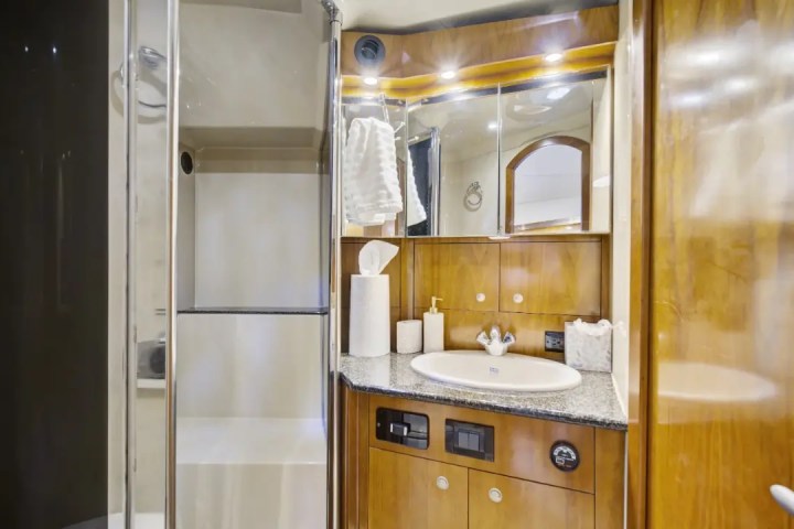Modern bathroom with wood cabinets, shower, and sink with toiletries.