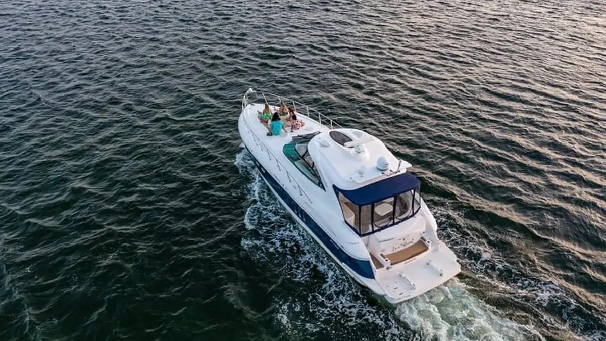 Aerial view of a boat with people on it cruising on the ocean.