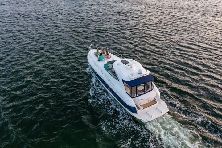 Aerial view of a boat with people on it cruising on the ocean.