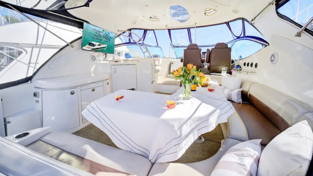 Inside view of a yacht with a dining area, flowers, and drinks on the table.