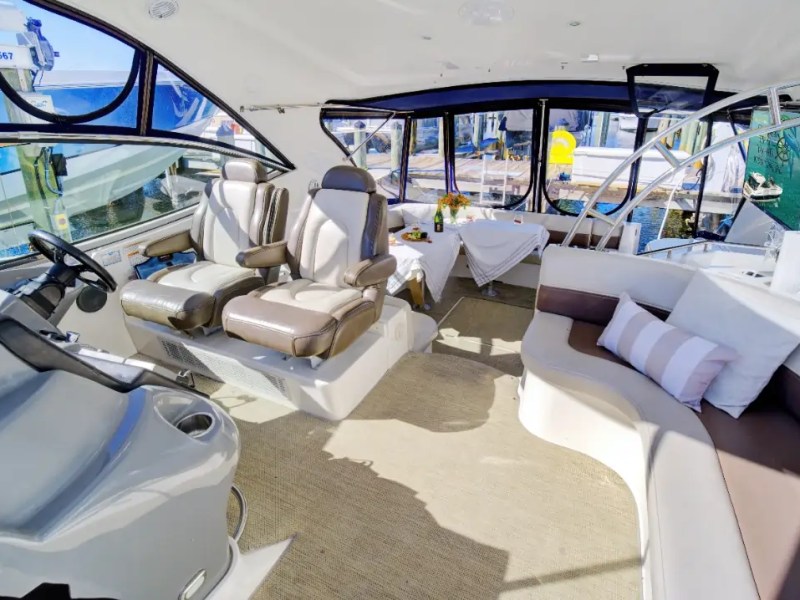 Interior of a luxury boat with plush seating, table, and steering area.