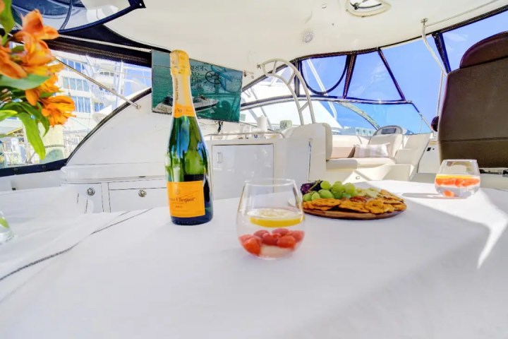 Luxurious boat interior with champagne, flowers, snacks, and drinks on a table.
