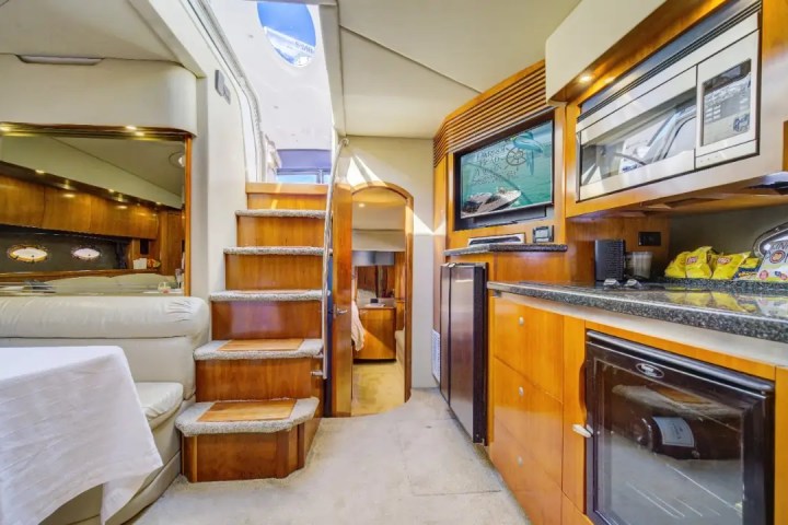 Interior of a yacht with a kitchen, stairs, and seating area visible.