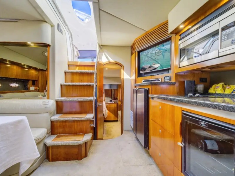 Interior of a yacht with a kitchen, stairs, and seating area visible.