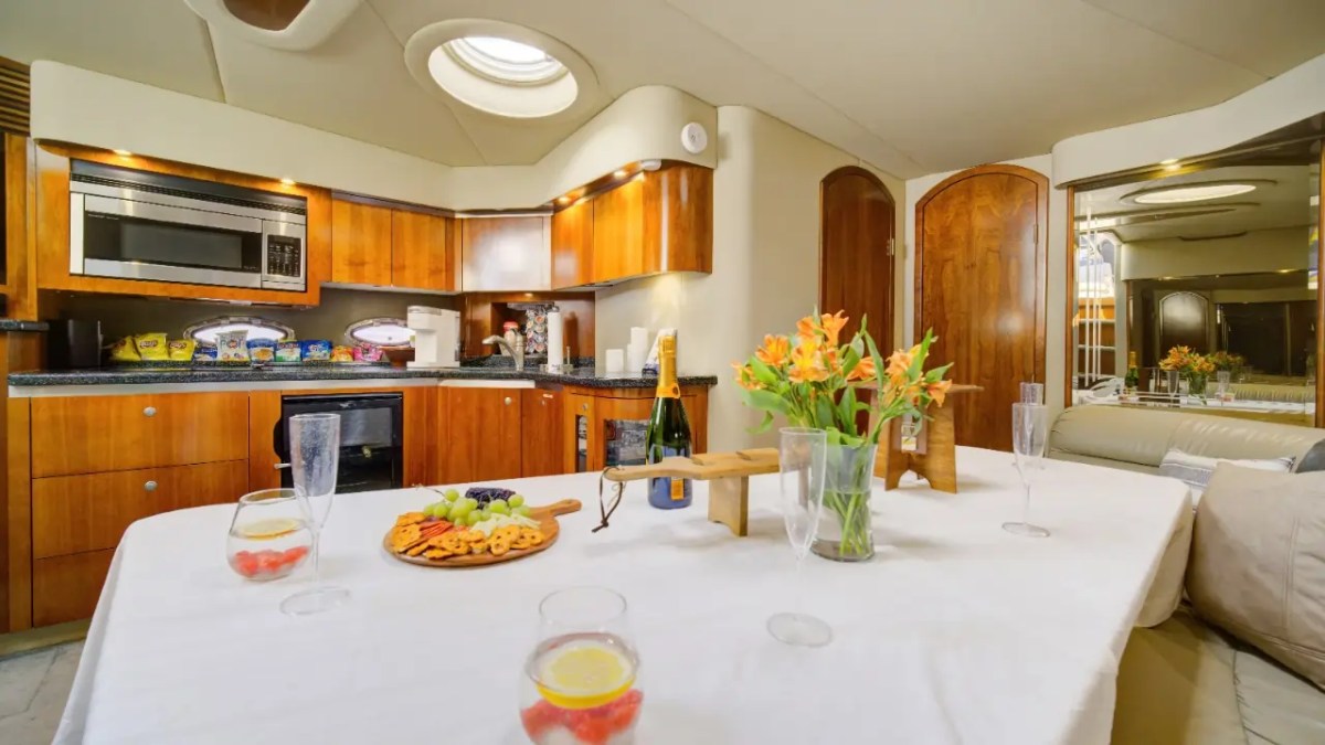 Luxury kitchen with wooden cabinets, table set with flowers, fruit platter, and champagne bottle.