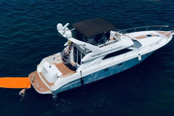 Aerial view of a yacht with an orange water mat on the ocean.