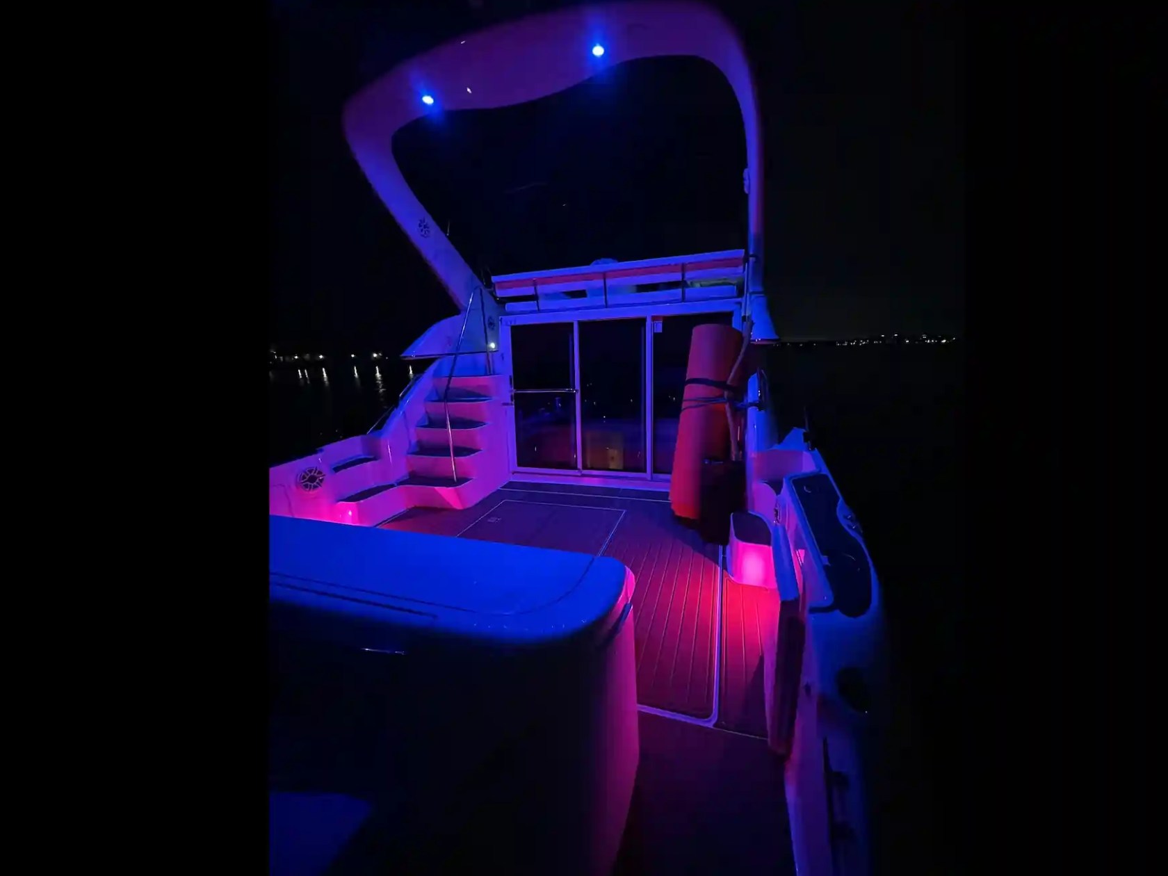 Boat deck illuminated with purple and blue lights at night.
