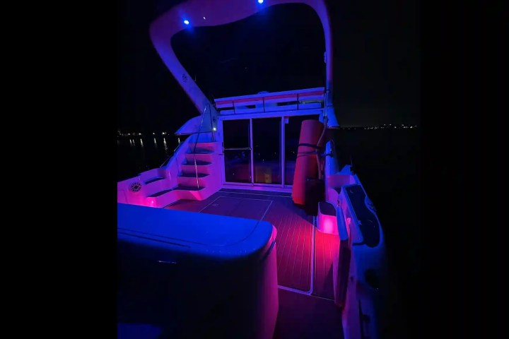 Boat deck illuminated with purple and blue lights at night.