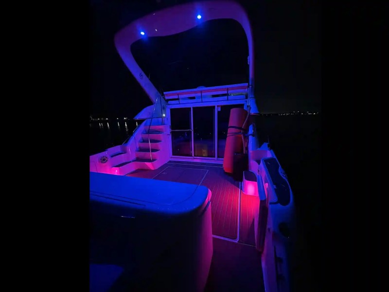 Boat deck illuminated with purple and blue lights at night.