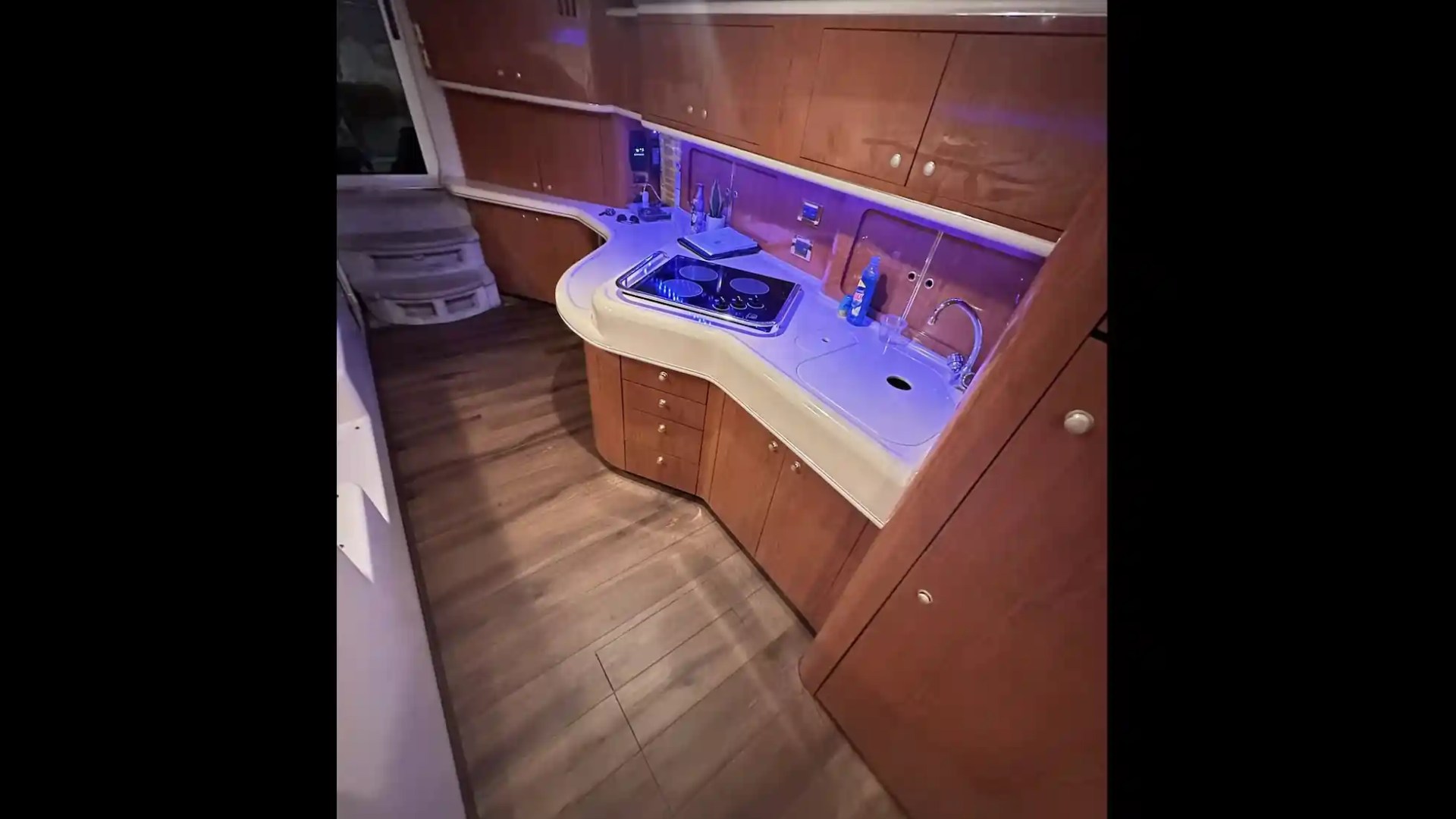 Small kitchen area on a yacht with wood cabinets, sink, and stove.