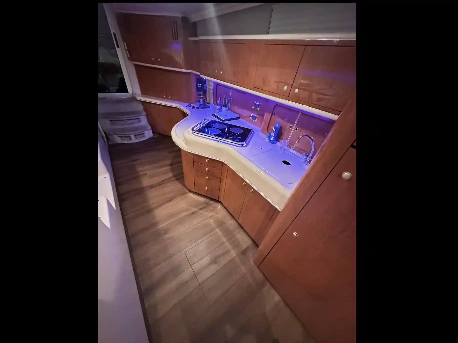 Small kitchen area on a yacht with wood cabinets, sink, and stove.