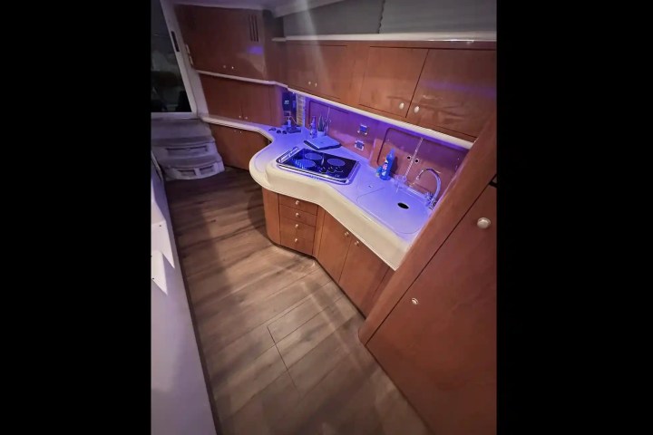 Small kitchen area on a yacht with wood cabinets, sink, and stove.