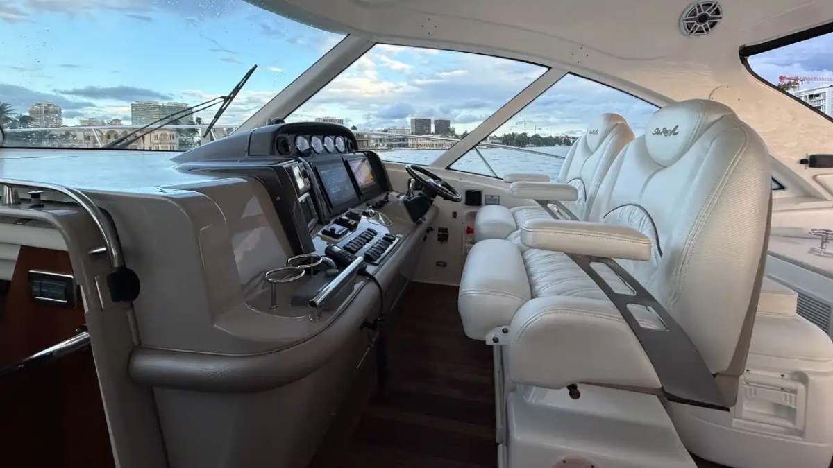 Interior of a yacht cockpit with white leather seats and navigation controls.